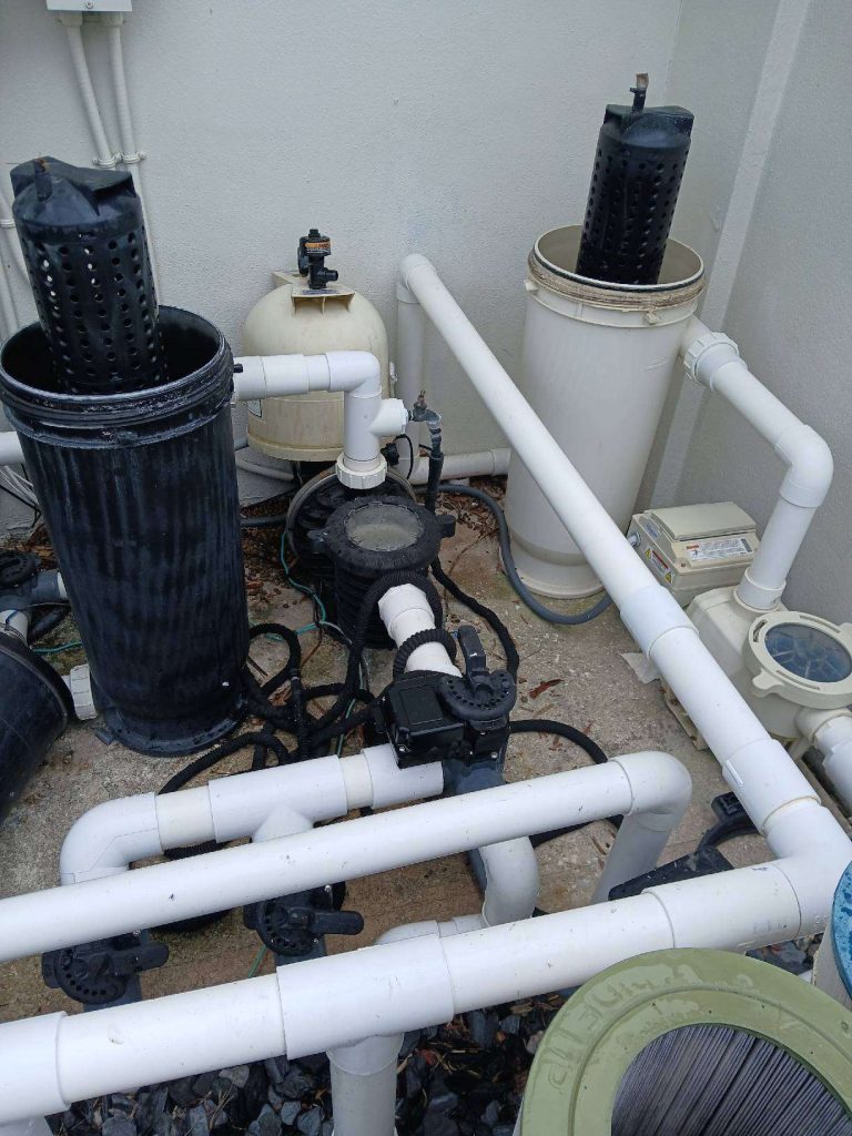Brevard County pool equipment pad with two black filters, a pump and white PVC plumbing, the suction and return lines checked during a leak search
